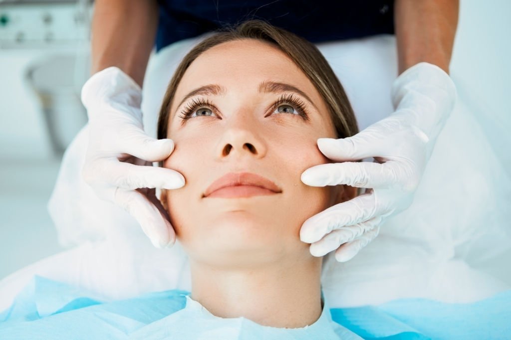 Cosmetologist preparing to doing cosmetic facial treatments for the young woman - Clinica Pellier Brasilia